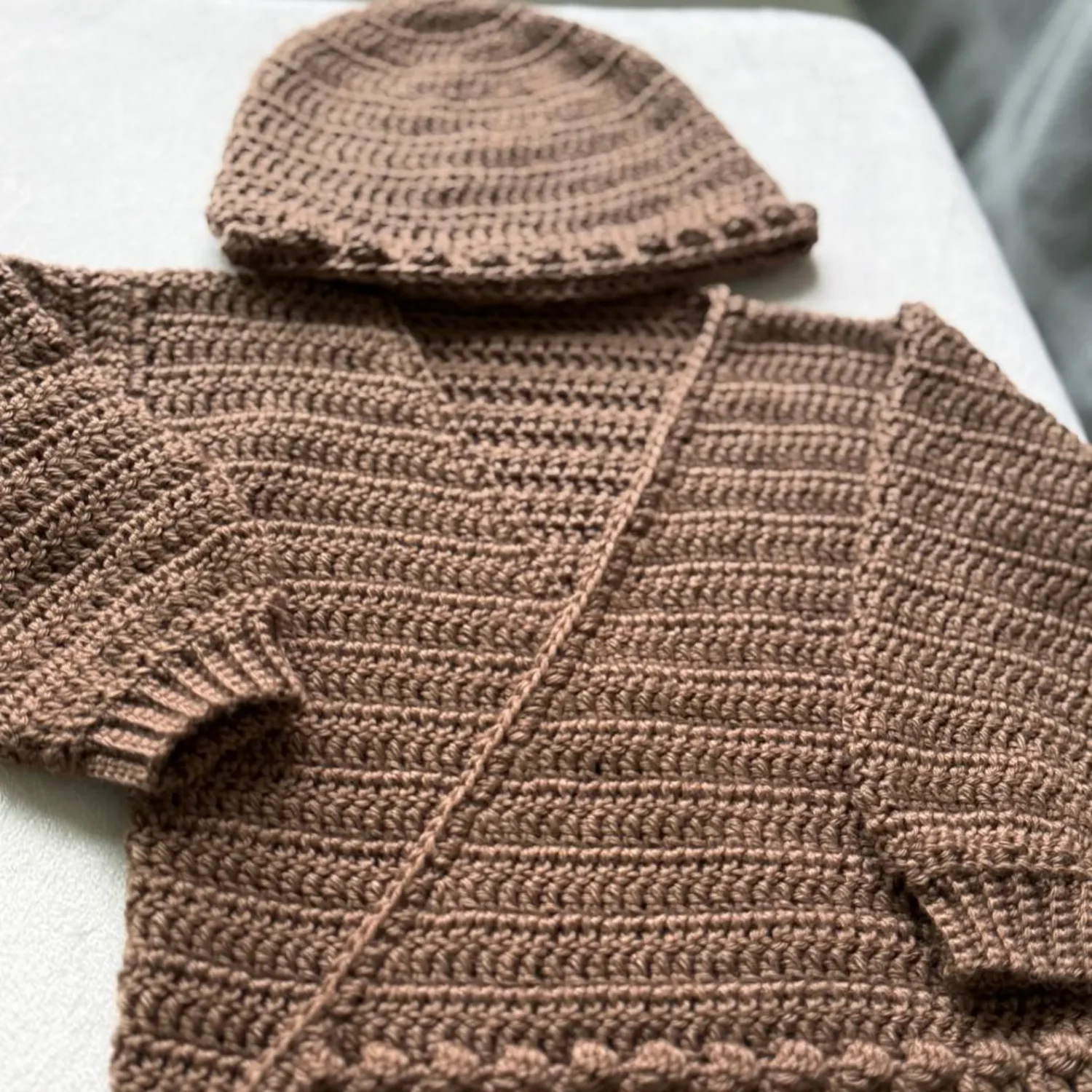 Brown Baby Wrap Sweater and matching Bobble Beanie laid flat